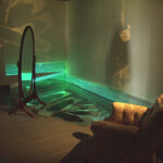 A. M. HOCH, interstices, DETAIL: living room with paintings on mirrors, video projections on baseboards, bureau with camera obscura, and video loops hidden inside various furniture and household objects, 12 x 15 feet, 2002